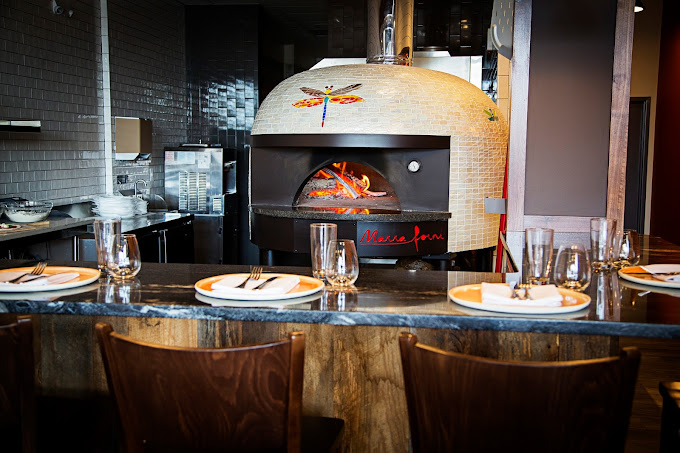 an image of a restaurant kitchen featuring a marra forni commercial wood-fired pizza oven. The oven has a custom logo of the restaurant inferno pizzeria napoletana