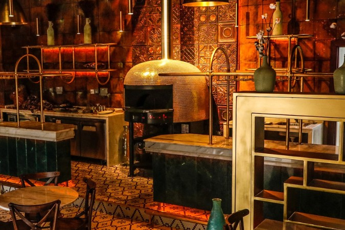 an image of a napo pizzeria from abu dhabi with a marra forni commercial brick pizza oven in the center of the room.
